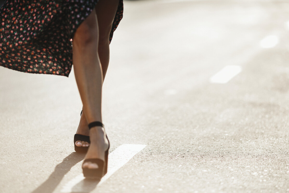 Front view of woman's legs on the high heels on the road on the sunny day