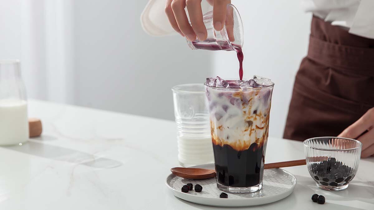 A man is making brown sugar vanilla pearl milk tea